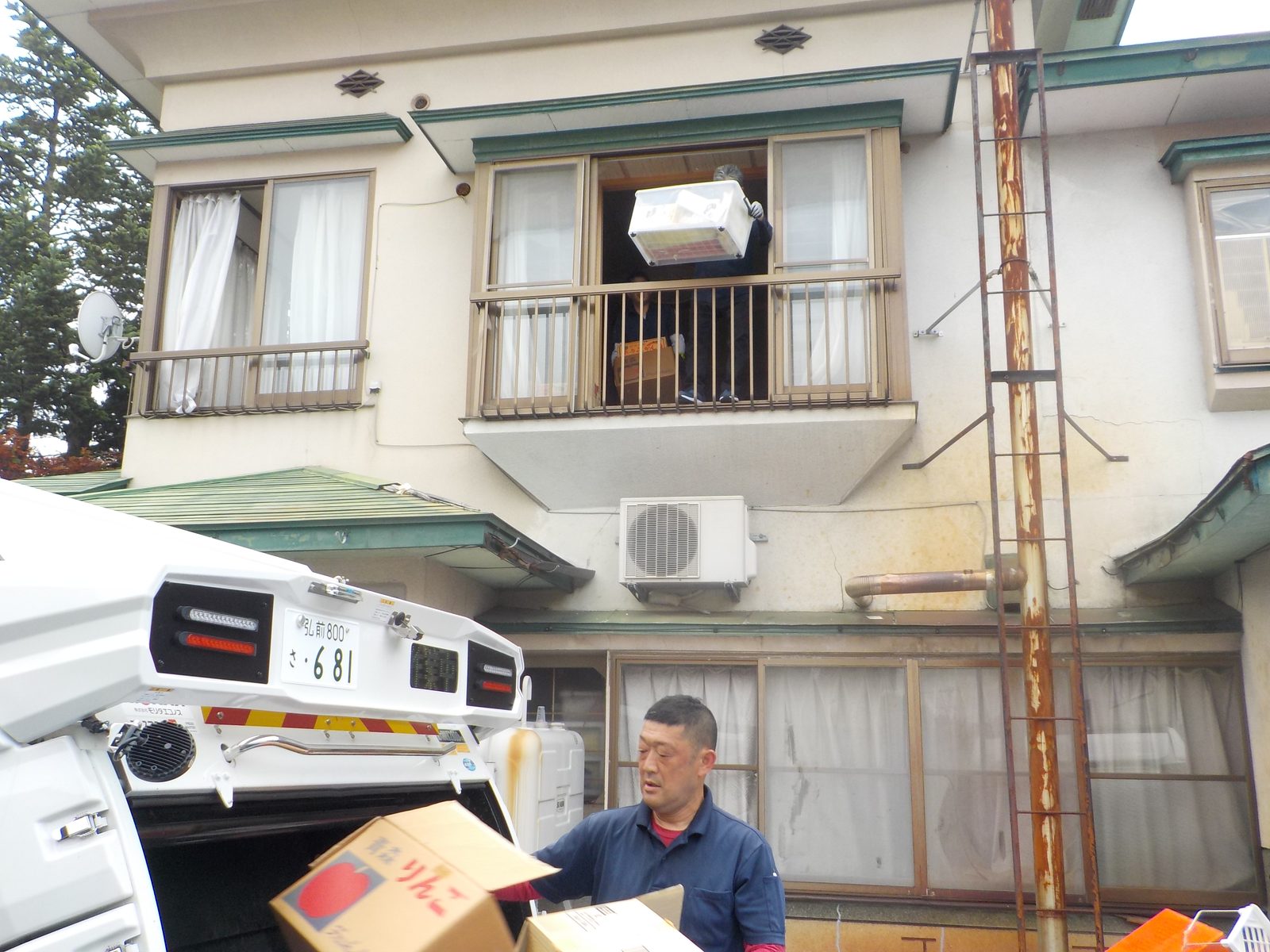 2階の窓から不用品を搬出する作業スタッフ