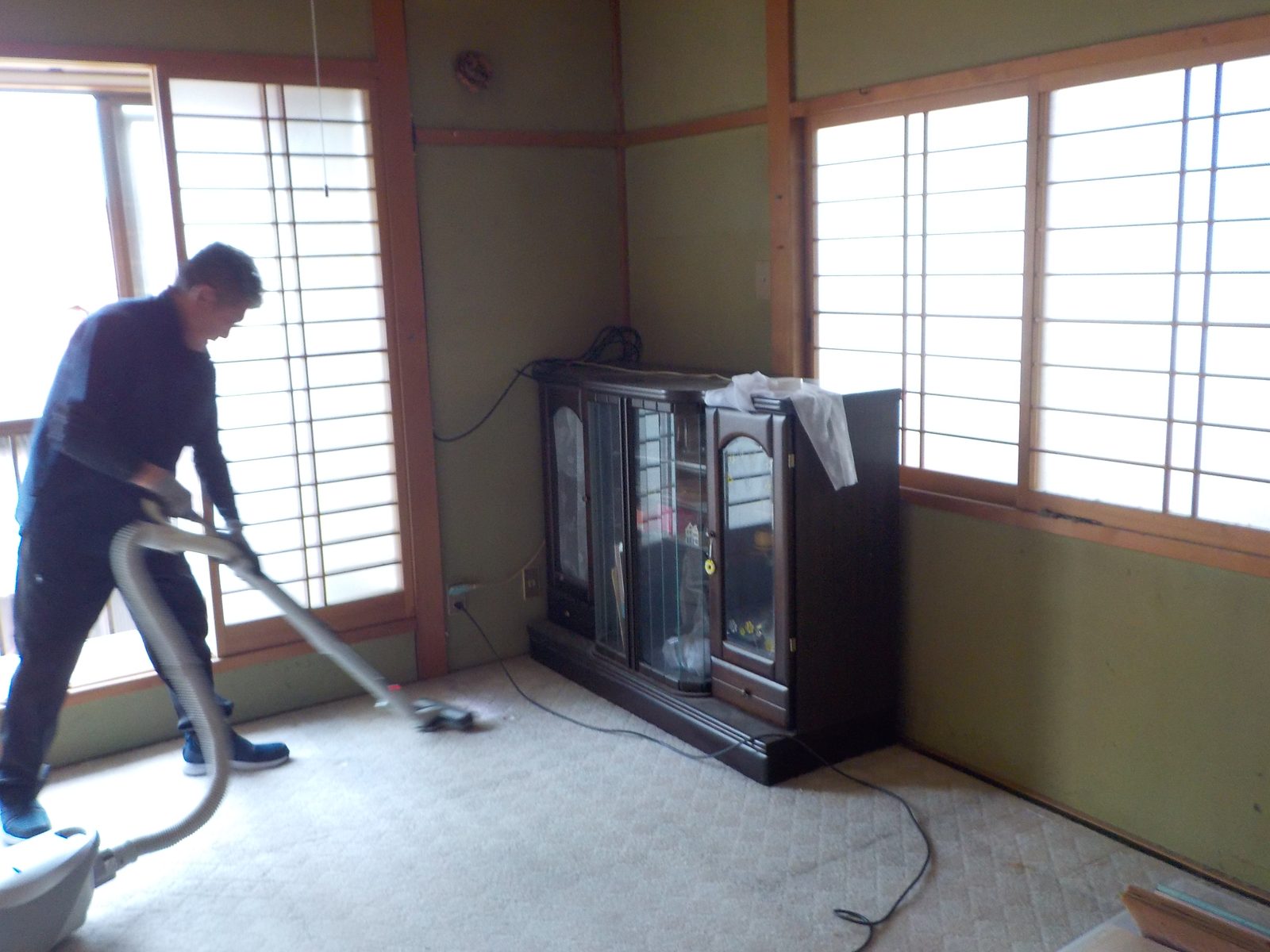 室内を掃除機がけする作業スタッフ